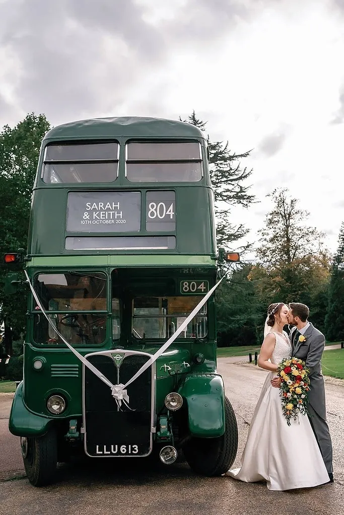 couple portrait in front of the green London Bus at Hanbury Manor