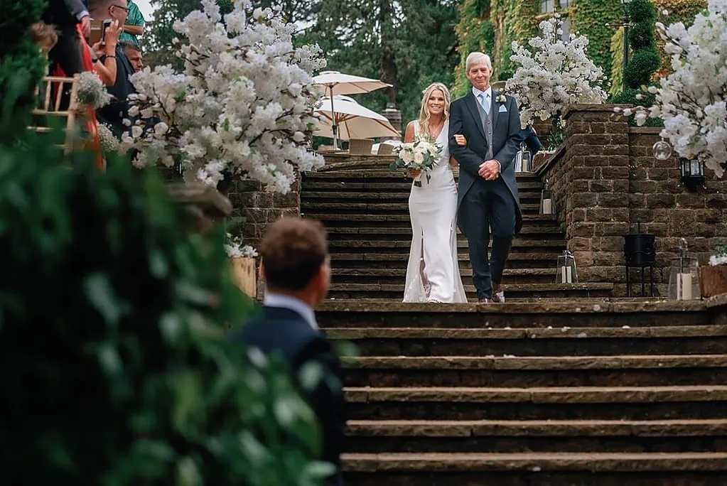 happy bride walking down the aisle at Pennyhill Park