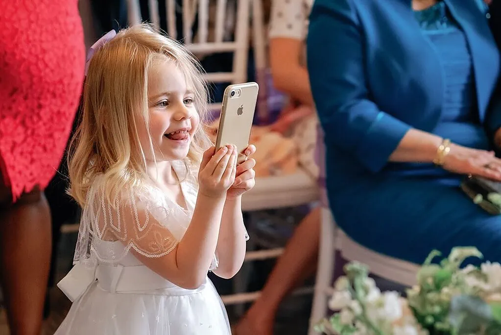 flower girl taking a photograph of the bride and groom