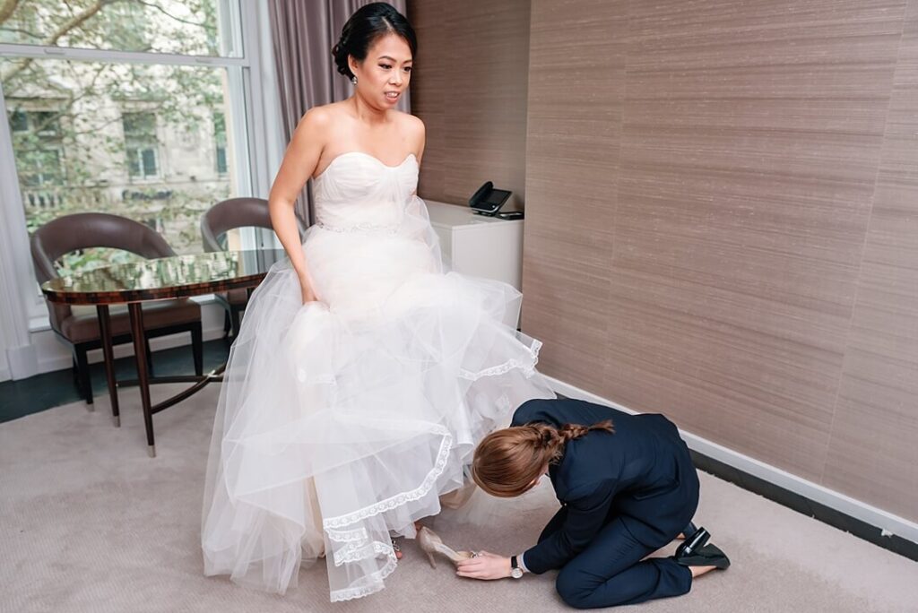bride putting on her shoes for the wedding photography at Corinthia Hotel London