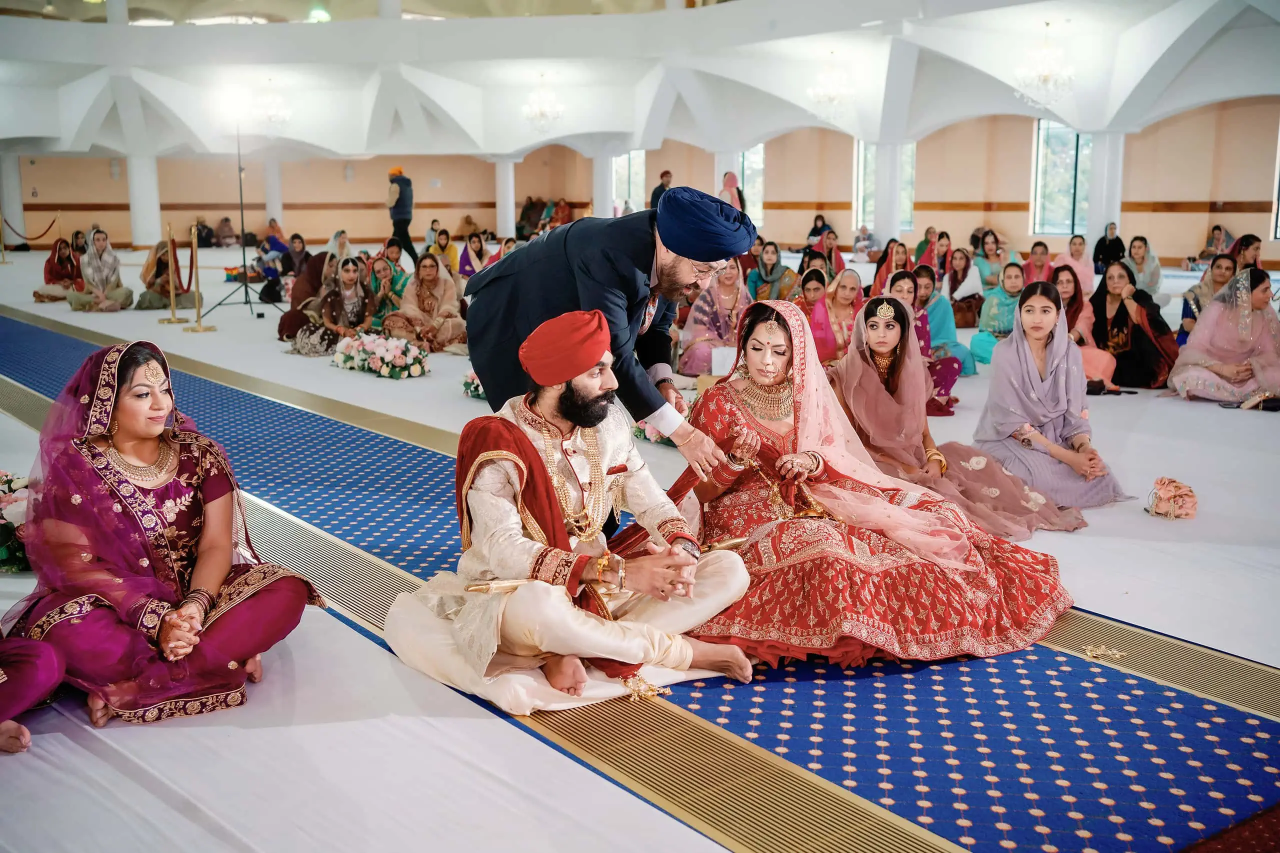 Bride’s father places one end of the Groom’s saffron-coloured palla in the Bride’s hand Sikh Wedding